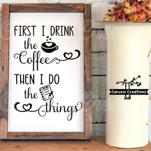 May include: A white wooden sign with black text that reads "First I drink the coffee then I do the things" with a coffee cup and a to-do list graphic. The sign is hanging on a white wooden wall.