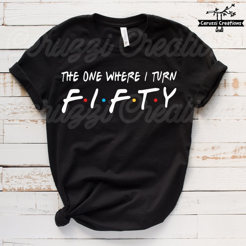 Może przedstawiać: Czarny T-shirt z białym tekstem, kt&oacute;ry brzmi "The One Where I Turn Fifty" z kolorowymi kropkami między literami.