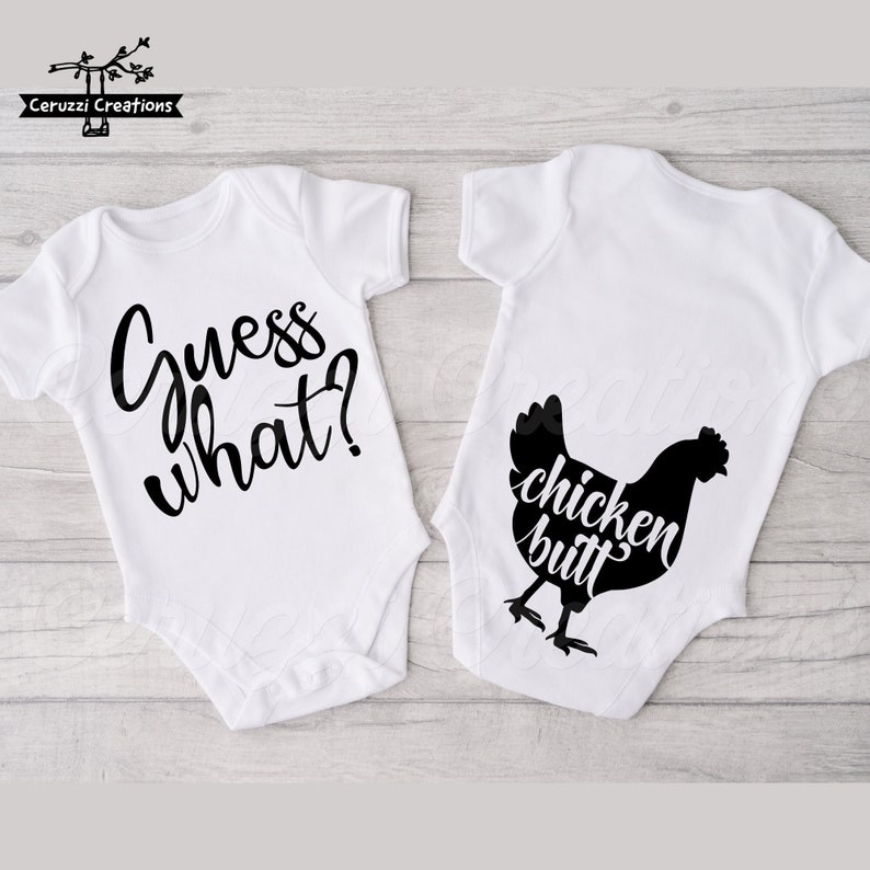 May include: Two white baby onesies. One has the text "Guess what?" in black script. The other has a black chicken silhouette with the words "chicken butt" in a playful font. Perfect for a baby shower gift.