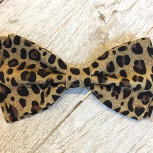May include: A brown and black leopard print bow tie.