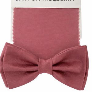 May include: A bow tie and fabric swatch in a dusty rose color, labeled "Chiffon Mulberry." The bow tie is centered at the bottom, with the fabric swatch above it. The fabric has a textured appearance.