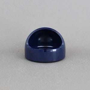May include: A dark blue ceramic ashtray shaped like a small bowl. The ashtray is designed to hold cigarette butts.