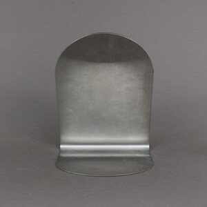 May include: A silver metal bookend with a rounded top and a flat base.
