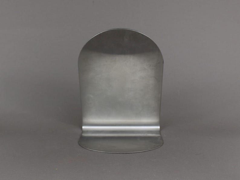 May include: A silver metal bookend with a rounded top and a flat base.