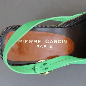 May include: Green leather heeled sandal with a brown leather insole. The insole has the text "PIERRE CARDIN PARIS" printed on it.