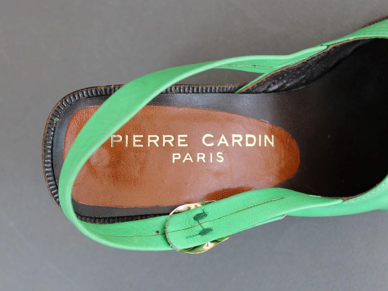 May include: Green leather heeled sandal with a brown leather insole. The insole has the text "PIERRE CARDIN PARIS" printed on it.