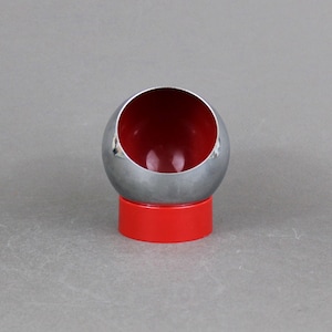 May include: A chrome and red ashtray shaped like a sphere with a cut-out for holding cigarettes.