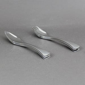 Può includere: Un set di sei forchette color argento con manici curvi.