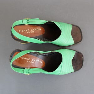 May include: A pair of green and brown platform sandals with the text "Pierre Cardin Paris" on the straps.
