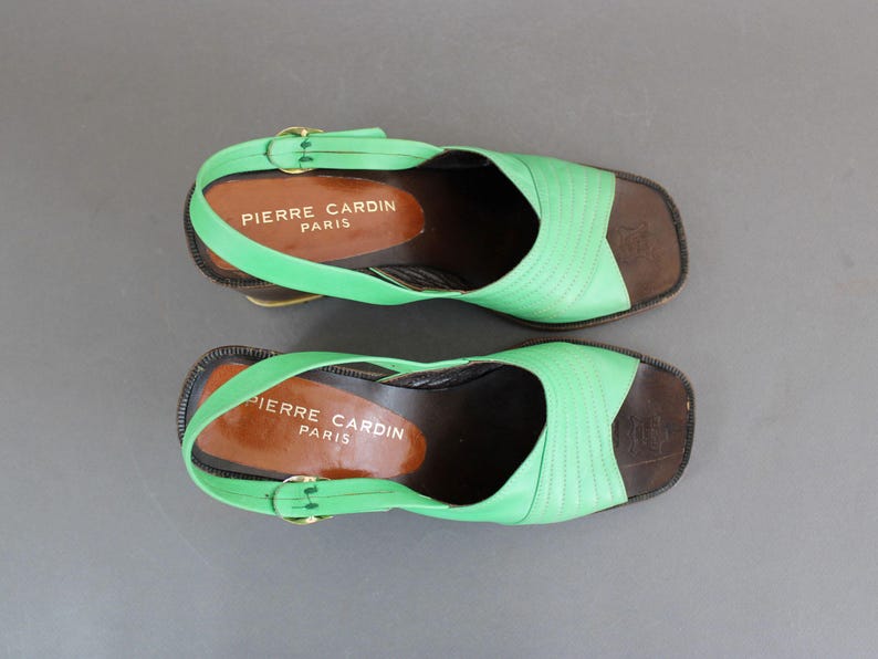 May include: A pair of green and brown platform sandals with the text "Pierre Cardin Paris" on the straps.