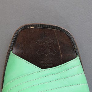 May include: Green leather sandals with a brown leather insole. The insole has the text "Leather Leder Cuir" and "Made in France" printed on it.