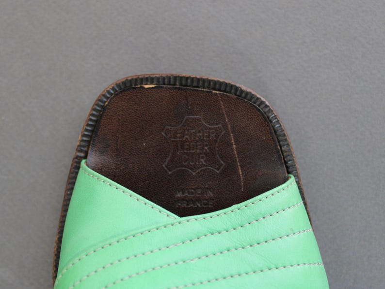 May include: Green leather sandals with a brown leather insole. The insole has the text "Leather Leder Cuir" and "Made in France" printed on it.
