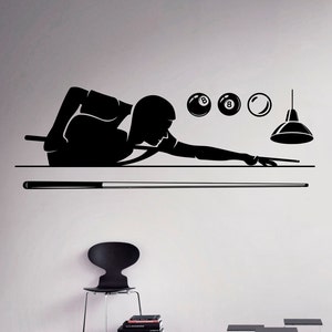 May include: Black and white silhouette of a person playing pool. The person is in a bent-over position, holding a pool cue and aiming at a ball. There are three billiard balls above the pool table, and a light fixture hanging from the ceiling.