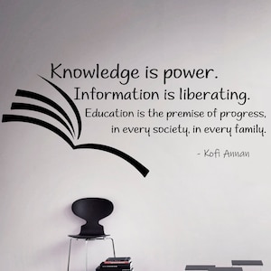 May include: Black and white text on a white wall with a black open book graphic. The text reads "Knowledge is power. Information is liberating. Education is the premise of progress, in every society, in every family. - Kofi Annan"