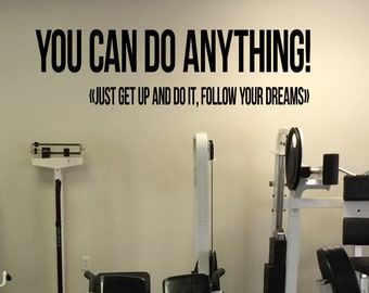 May include: A motivational wall decal in a gym setting. The black text reads "YOU CAN DO ANYTHING!" with the phrase "JUST GET UP AND DO IT, FOLLOW YOUR DREAMS" below. Gym equipment, including a scale and weight machines, are visible.