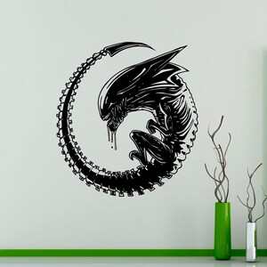 May include: Black and white alien creature decal in a circle shape. The alien is curled up with its tail forming the circle.
