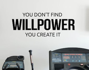 May include: A white wall with the text "YOU DON'T FIND WILLPOWER YOU CREATE IT" in black lettering. Two black elliptical machines are in the background.