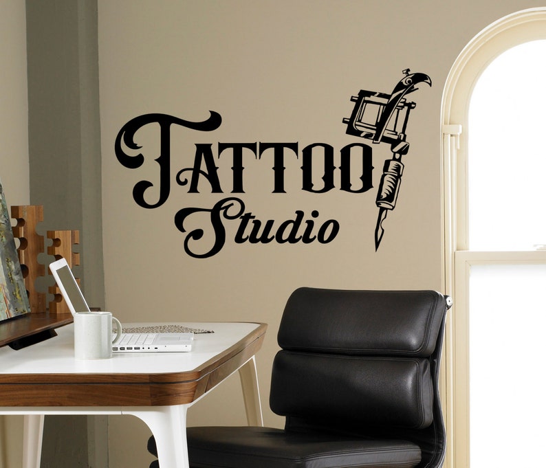 May include: Black and white tattoo studio sign with a stylized tattoo machine and the text "Tattoo Studio".