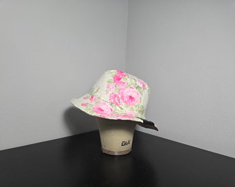 May include: A white bucket hat with a pink floral print. The hat is on a mannequin head.
