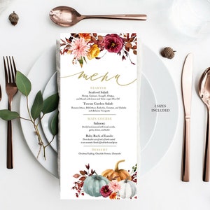 May include: A menu card with a floral design and the word "menu" in gold script. The menu features a fall theme with pumpkins and flowers. The card is placed on a white plate with copper-colored cutlery.