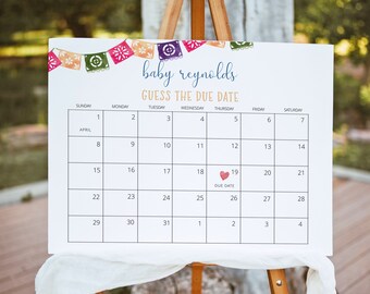 May include: A white sign on a wooden easel with the text "baby reynolds GUESS THE DUE DATE" and a calendar grid. The calendar shows the month of April with a heart on the 19th, labeled "DUE DATE". Colorful banner decorations are at the top.