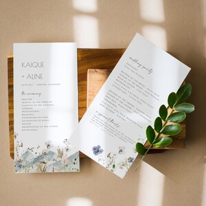 May include: Wedding ceremony program with a watercolor floral design. The program lists the order of events for the ceremony, including the seating of the families, lighting of the candles, and the processional. The wedding party is listed on a separate page with a similar floral design.