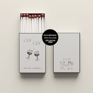 May include: Two white matchboxes with black trim. The left box has a black and white illustration of two wine glasses with the text "CIN CIN" and "olivia + martin". The right box has a black and white illustration of a couple dancing with the text "OEM".