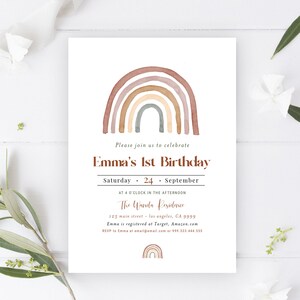 May include: A white invitation card with a watercolor rainbow design in shades of brown, tan, and gray. The text reads "Emma's 1st Birthday" with event details. The card is decorated with floral accents.