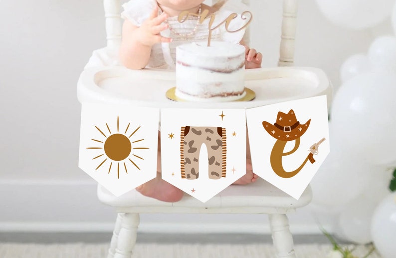 May include: A banner with three white pennants, each featuring a different design in brown. The designs include a sun, pants, and a cowboy hat with the letter "E" and a gun. The banner is part of a first birthday celebration.