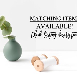 May include: A small, sage green vase holds a sprig of eucalyptus. Two wooden spools with white ribbon are in the foreground. Text reads "MATCHING ITEMS AVAILABLE! Check listing description!"