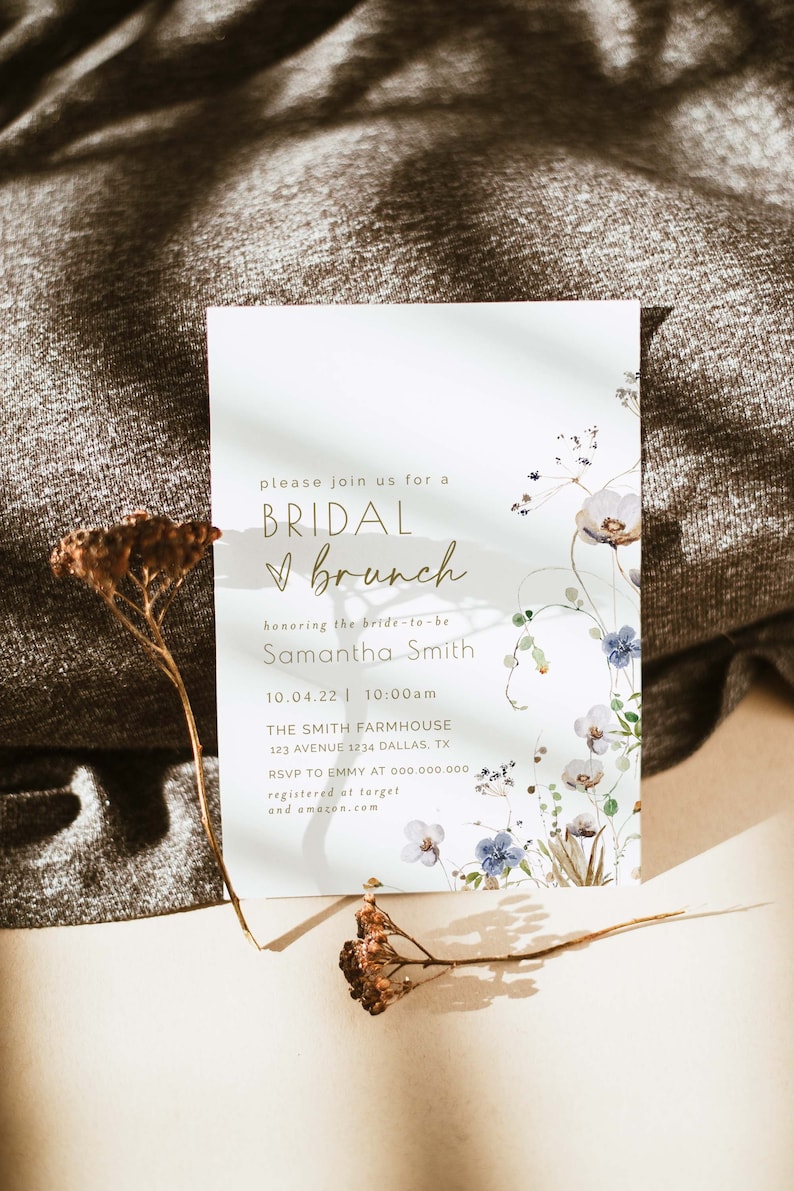 May include: A white invitation card with a floral design and gold lettering. The text reads "Please join us for a Bridal Brunch honoring the bride-to-be Samantha Smith 10.04.22 | 10:00am The Smith Farmhouse 123 Avenue 1234 Dallas, TX RSVP to Emmy at 000.000.000 registered at target and amazon.com"