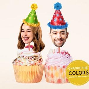 May include: Two cupcakes with colourful frosting and sprinkles. Each cupcake has a person's face on a stick, wearing a party hat. The text on the yellow sign says "Change the Colours, Best Price, Best Service."