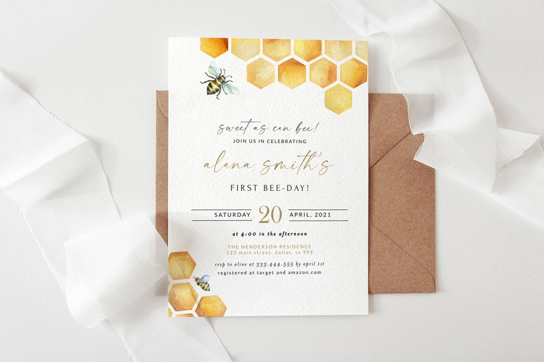 May include: A white invitation card with gold lettering and a watercolor illustration of a honeycomb and a bee. The text reads "Sweet as can bee! Join us in celebrating Alana Smith's First Bee-Day! Saturday, April 20, 2021 at 4:00 in the afternoon. The Henderson Residence, 123 Main Street, Dallas, TX 399. RSVP to Alana at 333-444-555 by April 1st. Registered at Target and Amazon.com"