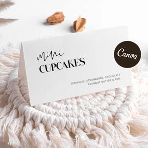 May include: A white folded card with black text reading Mini CUPCAKES and a list of flavors including sprinkles, strawberry, chocolate, peanut butter, and red. A dark brown circle with the word Canva is printed on the right side of the card.