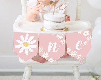 Könnte beinhalten: Rosa-weißer Hochstuhl-Banner mit dem Wort "eins" in weißer Schrift und einem Gänseblümchenmuster.