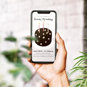 Peut inclure: Un smartphone affichant une invitation d'anniversaire pour le 21e anniversaire d'Amanda. L'invitation repr&eacute;sente un g&acirc;teau au chocolat avec des bougies roses et des fleurs blanches. Le texte indique "Rejoignez-nous pour c&eacute;l&eacute;brer le 21e anniversaire d'Amanda. Le 23 avril &agrave; 15h00. Le restaurant Milo."