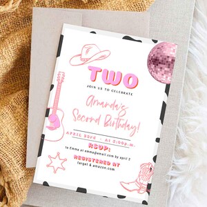 May include: A pink and white birthday invitation with a cow print background. The invitation says "Two" in pink letters with a pink and white cowboy hat, a pink disco ball, a pink guitar, and a pink cowboy boot. The text says "Join us to celebrate Amarda's Second Birthday! April 23rd at 5:00p.m. RSVP to Emma at emma@email.com by April 2. Registered at target & amazon.com"