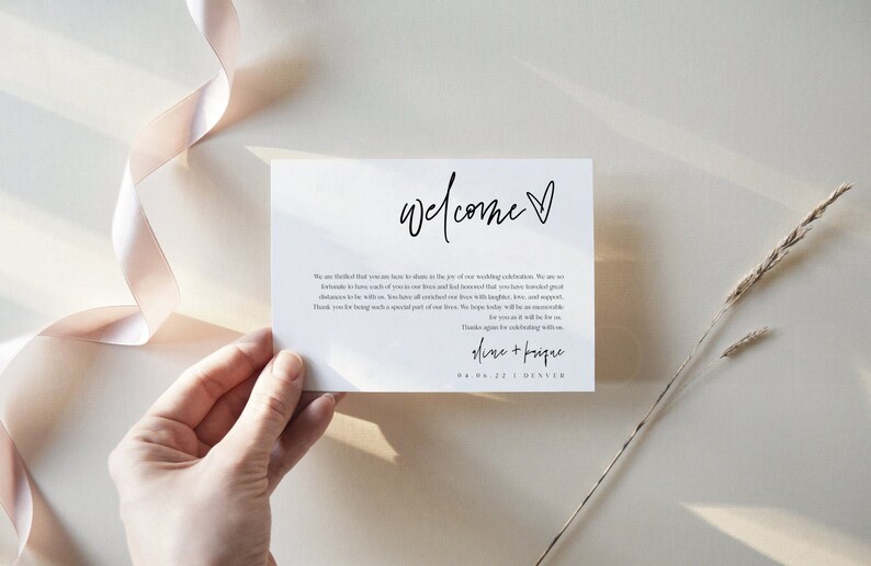May include: A white welcome sign with black calligraphy that reads "welcome" with a small heart. The text below reads "We are thrilled that you are here to share in the joy of our wedding celebration. We are so fortunate to have each of you in our lives and feel blessed that you have traveled great distances to be with us. We have cherished all our time with you, your laughter, and support. Thank you for being such a special part of our lives. We hope today will be an unforgettable celebration. Thank you again for celebrating with us.  Alana +  Bosque 08.06.22 | Denver"