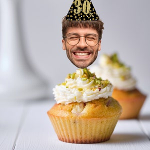 K&ouml;nnte beinhalten: Ein Cupcake mit wei&szlig;em Frosting und gr&uuml;nen Streuseln, gekr&ouml;nt mit einer schwarzen und goldenen Partym&uuml;tze mit der Nummer 30.