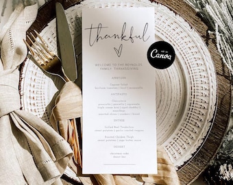 May include: A Thanksgiving table setting with a menu card that reads "thankful." The card is on a white plate with a gold fork and knife. A gold spoon is visible in the background. The menu lists appetizers, antipasto, entree, and dessert.