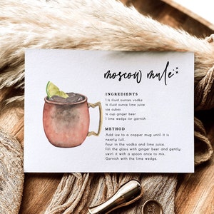 Puede incluir: Una tarjeta de receta para un c&oacute;ctel Moscow Mule con una ilustraci&oacute;n de acuarela de una taza de cobre llena de una bebida oscura y una rodaja de lima. La receta incluye los ingredientes y las instrucciones para preparar el c&oacute;ctel.