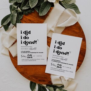 May include: Two white cards with black text that reads "i did i do i done!"  The text is in a retro font. The cards are invitations to a celebration for Amanda. The invitations state "The divorce is final... so it's time to celebrate!" and "Let's get together to celebrate new beginnings for Amanda." The invitations are set on a wooden surface with white fabric and green leaves.