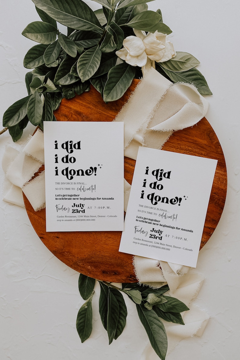 May include: Two white cards with black text that reads "i did i do i done!"  The text is in a retro font. The cards are invitations to a celebration for Amanda. The invitations state "The divorce is final... so it's time to celebrate!" and "Let's get together to celebrate new beginnings for Amanda." The invitations are set on a wooden surface with white fabric and green leaves.