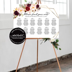 Puede incluir: Un plano de asientos de boda en un caballete de madera. El letrero blanco presenta un arreglo floral con flores burdeos y color rubor. Acentos geom&eacute;tricos dorados enmarcan la lista de asientos, con el texto "Please find your seat".