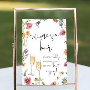 May include: A printable sign with a floral border and the text "mimosa bar". The sign instructs guests to pour bubbly juice, add some fruit, and enjoy.