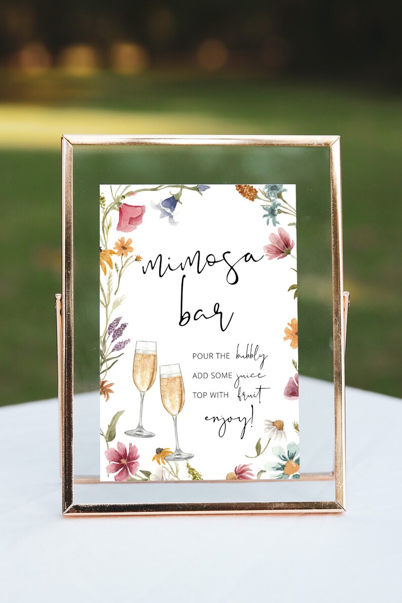 May include: A printable sign with a floral border and the text "mimosa bar". The sign instructs guests to pour bubbly juice, add some fruit, and enjoy.