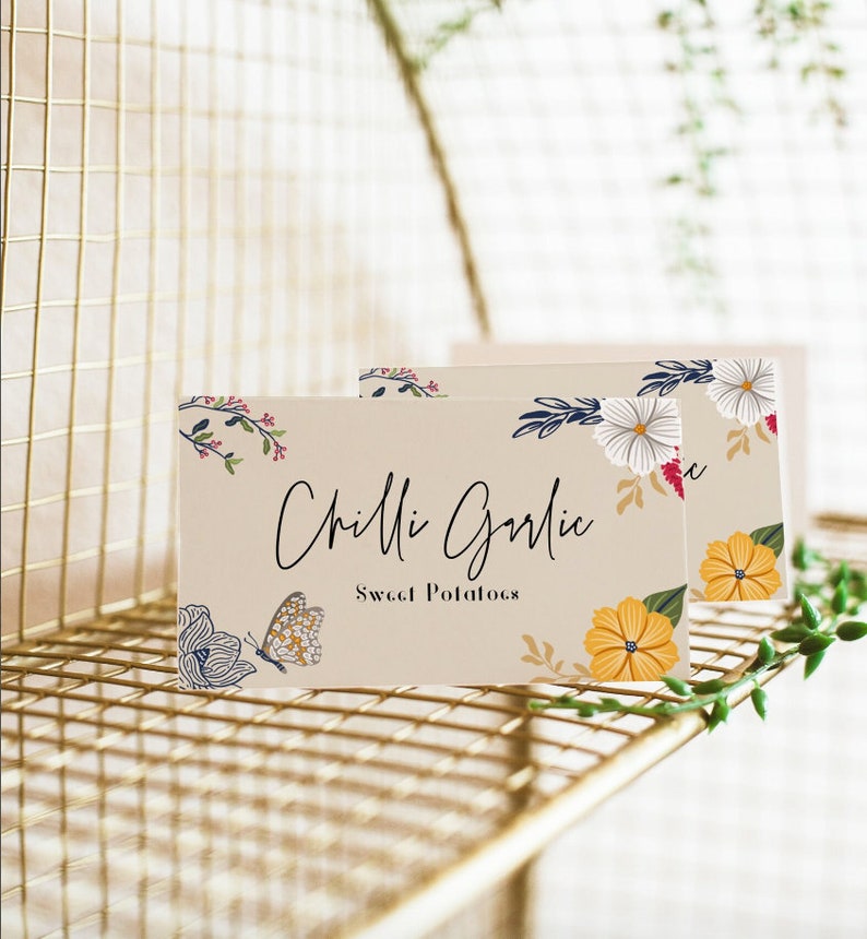 Puede incluir: Dos tarjetas de lugar beige con dise&ntilde;os florales y el texto "Chilli Garlic Sweet Potatoes" impreso en negro.