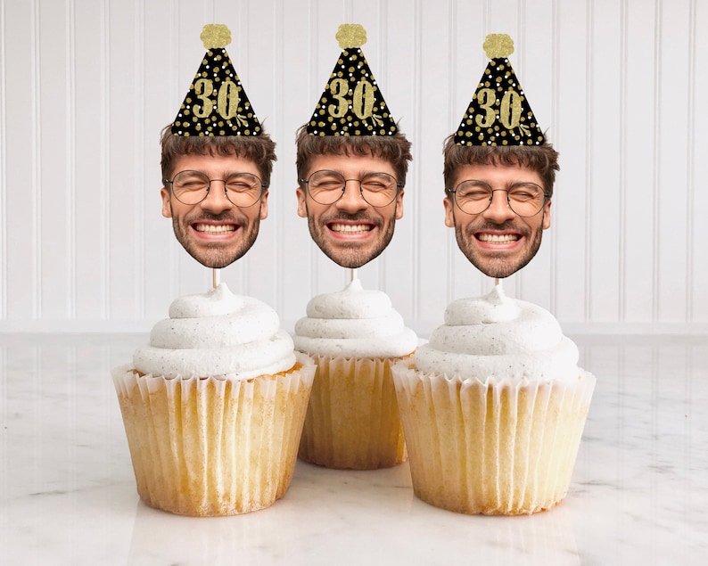 K&ouml;nnte beinhalten: Drei Cupcakes mit wei&szlig;em Frosting und schwarzen und goldenen Partyh&uuml;ten mit der Nummer 30 darauf. Die H&uuml;te haben ein Gesicht mit Brille und einem L&auml;cheln.