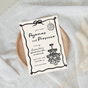 May include: A black and white illustration of a disco ball and champagne glasses on a cream-colored card with the text "Joining for Pajamas and Prosecco honoring Camille's bachelorette weekend April 23rd-26th Charlotte, NC Itinerary for details"