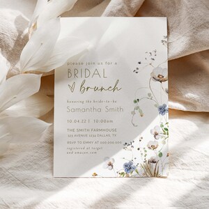 May include: A white card with gold text announcing a bridal brunch for Samantha Smith. The card is decorated with watercolor flowers and greenery. The event is scheduled for 10.04.22 at 10:00am at The Smith Farmhouse, 123 Avenue 1234 Dallas, TX. RSVP to Emmy at 000.000.000. The couple is registered at Target and Amazon.com.